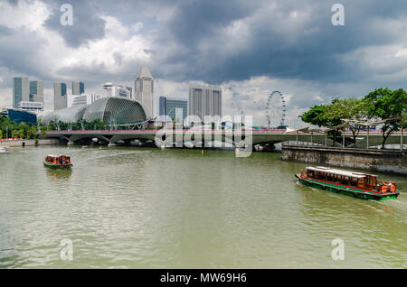 Eine Kreuzfahrt Boot wie die twakows Fahrt durch die berühmten Singapore River bekannt. Das Gebäude an der Rückseite ist die berüchtigte Theater an der Bucht, Esplanade. Stockfoto