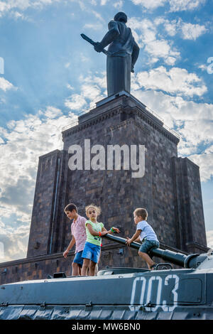 Yerevan, Armenien - 20. August 2017: Kinder spielen auf dem Tank mit Mutter Armenien Denkmal hinter, im Park des Sieges in Eriwan. Stockfoto