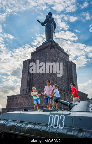 Yerevan, Armenien - 20. August 2017: Kinder spielen auf dem Tank mit Mutter Armenien Denkmal hinter, im Park des Sieges in Eriwan. Stockfoto