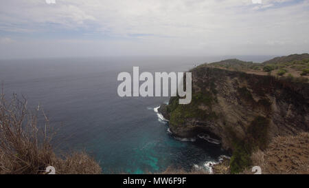Klippe mit Wellen gegen rocky shore, Nusa Penida, Indonesien. Felsige Küste und Meer mit Wellen und felsigen Klippen. Travel Concept. Stockfoto