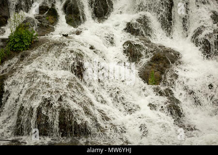 Schnell fließendes Wasser, das über nassen Felsen plätschern und fließen kann Stockfoto