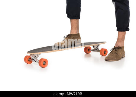 7/8 Schuß von den eleganten jungen Mann stehen auf Skateboard isoliert auf weißem Stockfoto