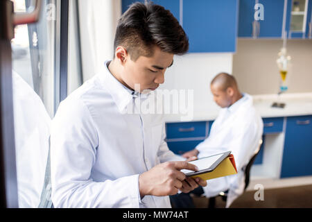 Junge Techniker in Laborkittel mit digitalen Tablette im Labor Umgebung Stockfoto