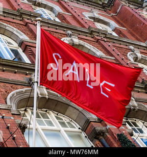 Einkaufen, Verkauf rote Flagge fliegen im Arnotts Kaufhaus, Brownstone Gebäude Fassade, auf Henry Street. Dublin Irland, Europa. Nahaufnahme, niedrige Winkelansicht. Stockfoto