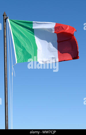 Italienische Flagge schwenkten mit sonnigen blauen Himmel Hintergrund Stockfoto
