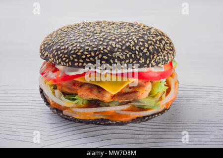 Schwarz Burger mit Fleisch Schnitzel und Gemüse auf einem Schneidebrett. Landhausstil. Burger mit Huhn auf weißem Holz- Hintergrund Stockfoto