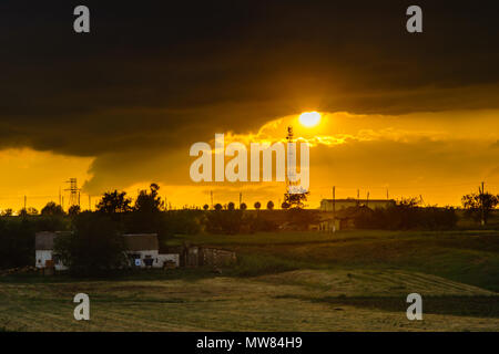 Sonnenuntergang über dem Feld mit Häuser im Dorf Stockfoto