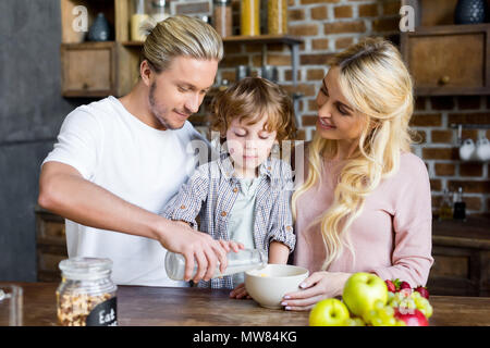 Glückliche junge Familie Vorbereitung corn flakes zum Frühstück zu Hause Stockfoto