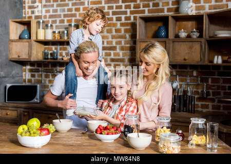 Glückliche Familie mit zwei Kindern vorbereiten und zum Frühstück zusammen zu Hause Stockfoto