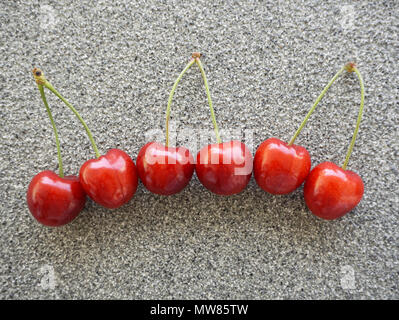 Frische rote Kirschen auf einem grauen Stein. Bio Lebensmittel Hintergrund oder wallpaper Stockfoto