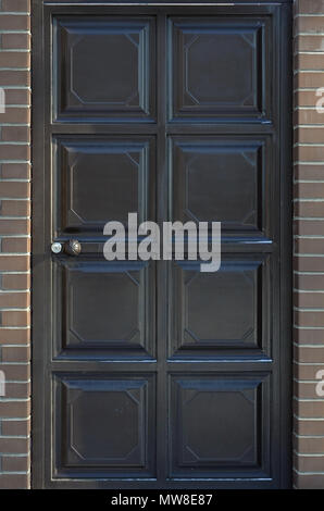 Die Textur einer lackiertem Metall Tür von einem Ziegelstein Zaun. Große Türen in der Wand der alten Ziegel gebaut Stockfoto
