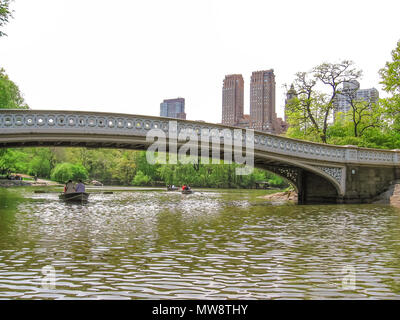 Die berühmten Bogen Brücke und Touristen auf Kanu im Hintergrund im Central Park, New York City, USA. Stockfoto