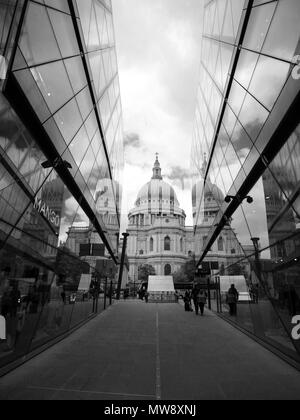 Schwarze und weiße Blick auf die St. Paul's Kathedrale, betrachtet aus zwischen zwei Gebäuden, in denen die Reflexion von St Paul's im Glas Gebäude.