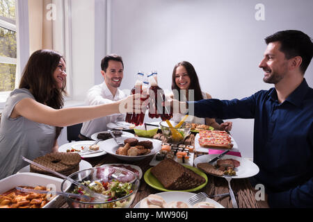 Glückliche junge Freunde Toasten mit Flaschen Bier auf einer Party Stockfoto