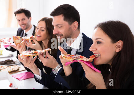 Nahaufnahme der Glückliche junge Geschäftsleute genießen Pizza Stockfoto