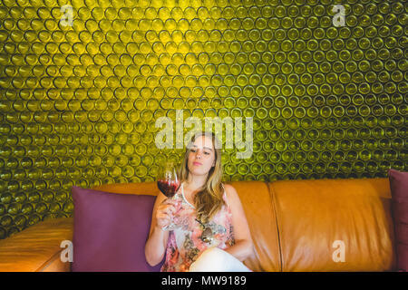 Schöne Frau Verkostung Wein mit Wein Flaschen im Hintergrund Stockfoto