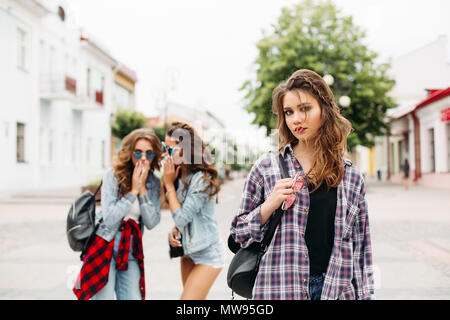 Eifersüchtig Mädchen Flüstern über dritte Mädchen vor der Kamera. Stockfoto