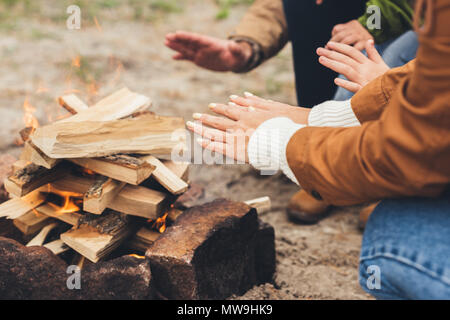 7/8 Schuß von Menschen Erwärmung der Hände mit Lagerfeuer Stockfoto