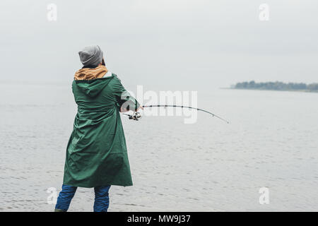 Einsamer mann Führungsschaft beim Angeln an regnerischen Herbsttag Stockfoto