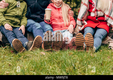 7/8 Schuß von Familie Herbst Schuhe tragen und zusammen sitzt im Park Stockfoto