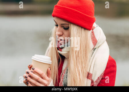 Schöne blonde junge Frau trinkt Kaffee aus dem pappbecher im Freien Stockfoto