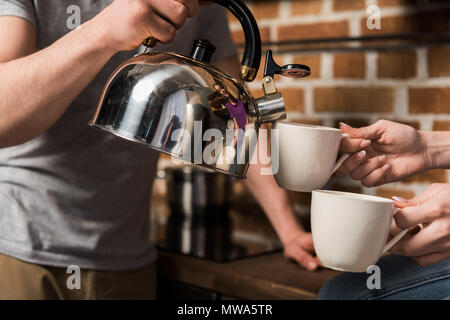 Zugeschnittenes Bild des Freundes gießen Kaffee in Tassen Stockfoto