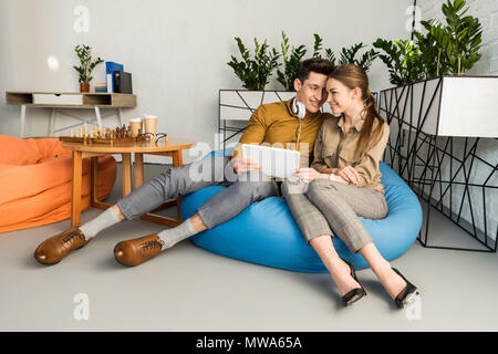 Junges Paar zusammen kuscheln beim Sitzen in Bean Bag mit Tablet Stockfoto