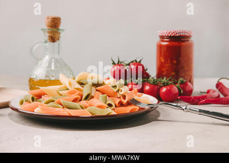 Bunte Nudeln auf dem Teller mit verschiedenen Speisen auf Hintergrund auf Betonoberfläche Stockfoto