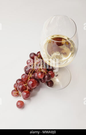 Blick von oben auf die weiße Glas Wein und Trauben auf Weiß Stockfoto