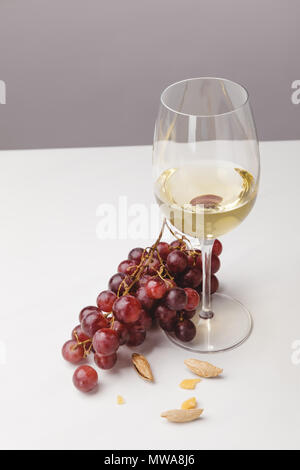 Detailansicht Weißwein Glas, Trauben und Mandeln auf Grau Stockfoto