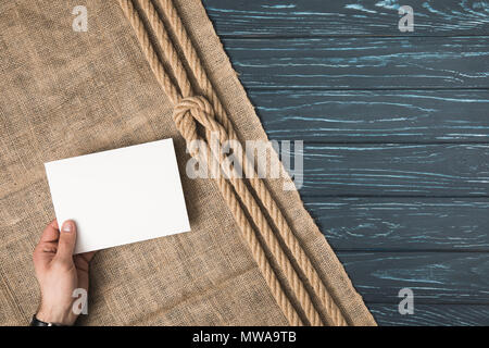 Zugeschnittenes Bild von Mann, leeres Papier einen Sack mit geknoteten Seil auf Holz- Oberfläche Stockfoto