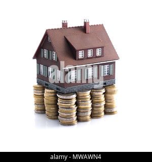 Modell Haus mit Stapel von Bargeld als Fundament: Investitionen, Darlehen und Immobilien Konzept Stockfoto