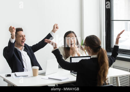 Aufgeregt diverse executive Kollegen heben die Hände feiern u Stockfoto