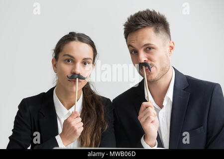 Lustige Kollegen machen dumme Gesichter holding Fake Schnurrbart, Köpfe Stockfoto
