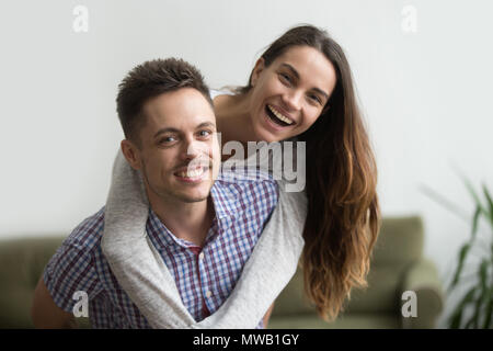 Lächelnd Mann huckepack fröhliche Frau zu Hause, glückliches Paar Stockfoto