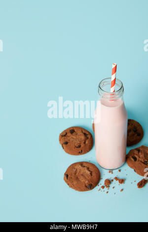 Detailansicht der Schokolade Cookies und Milchshake in Flasche mit Strohhalm auf blauem Hintergrund Stockfoto