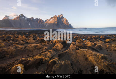 Schwarzen Sandstrand, bewachsene Steine, Berge, und Eystrahorn Klifatindur Kambhorn, landspitze Stokksnes, massiv Klifatindur Stockfoto