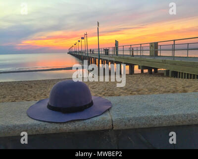 Woman's Hut auf einem Felsvorsprung in der Nähe von hölzernen Pier bei Sonnenuntergang vergessen Stockfoto