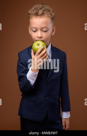 Junge als Geschäftsmann gegen braunen Hintergrund Stockfoto