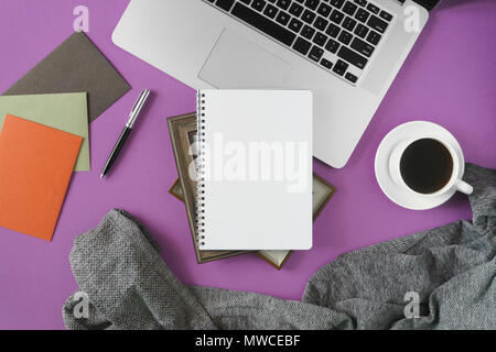 Home Arbeitsbereich mit Notebook, Laptop und Kaffee auf Pastell violett unterlegt. Home office flach Ansicht von oben. Stockfoto