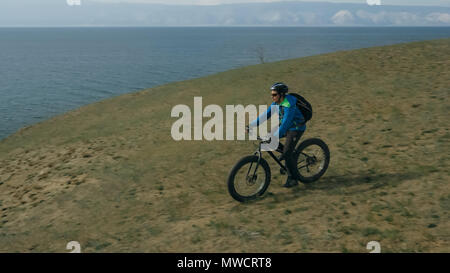 Fat bike auch fatbike oder Fat Tire Bike im Sommer fahren durch die Hügel. Der Mann ist mit dem Fahrrad entlang der Sand und Gras hoch in den Berg Stockfoto