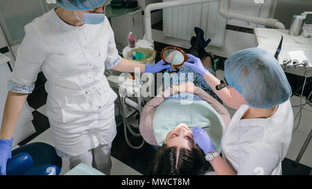 Frau beim Zahnarzt Klinik erhält der zahnmedizinischen Behandlung ein Loch in einen Zahn zu füllen. Zahnersatz und Verbundmaterial Polymerisation mit UV-Licht und Stockfoto