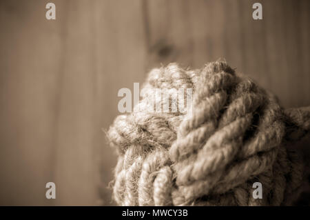 Kotflügel-marine Knoten der dicke braune Seil auf einer hölzernen Hintergrund, Nahaufnahme, getönt Stockfoto