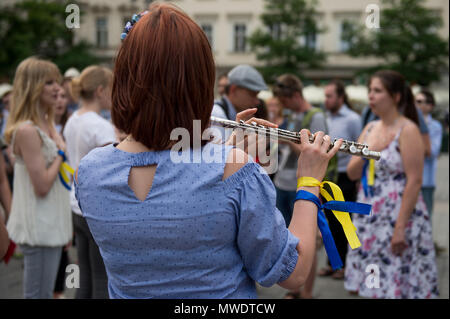 Ein Mädchen spielt Querflöte mit ukrainischen flags Farben während eines Protestes die Freilassung der Ukrainischen Filmemacher und Schriftsteller, Oleg Sentsov am Hauptplatz in Krakau. Oleg Sentsov wurde durch ein russisches Gericht am 25. August 2015 zu 20 Jahre für die Planung eines terroristischen Angriffs auf die Krim Halbinsel im Anhang durch Russland im April 2014 verurteilt. Stockfoto