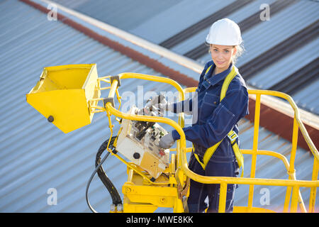 Weibliche Bauarbeiter vor Ort in hydraulische Hebebühne Stockfoto