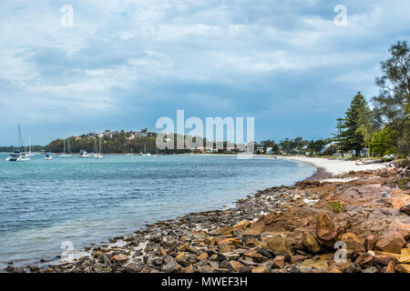 Anzeigen von Salamander Bay, NSW, Australien, mit Steinen in den Vordergrund und Yachten im Hafen. Stockfoto