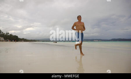 Mann laufen Strand entlang. Fitness Sport runner Mann Jogging am Strand. Hübscher junger fit Sportlich männlichen Athleten laufen außerhalb an einem wunderschönen Strand. Stockfoto