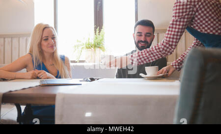 Kellner im Cafe bringt Tee für junge Paare Stockfoto