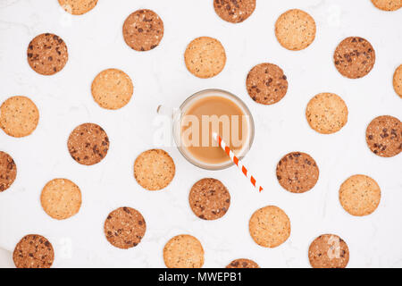 Tasse Kaffee unter Muster von verschiedenen Shortbread und Hafer cookies mit Müsli und Rosinen auf schwarzem Holz- Hintergrund. Ansicht von oben, flach. Stockfoto