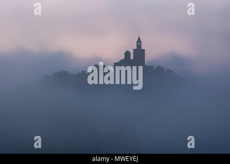 Super schöne Aussicht auf Tsarevets Festung in Veliko Tarnovo, Bulgarien an einem nebligen Sonnenaufgang im Sommer. Stockfoto